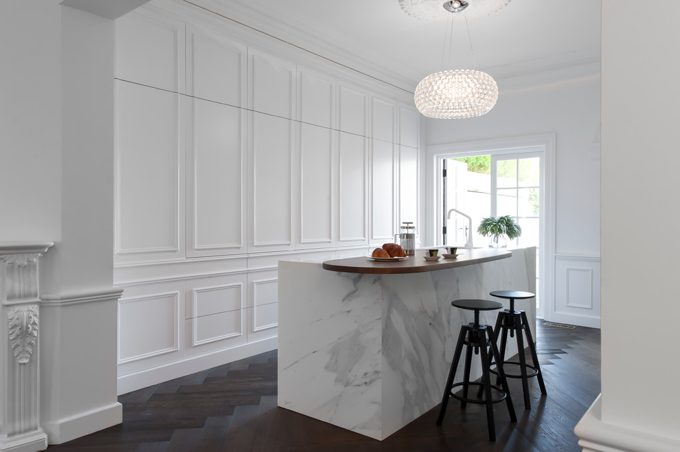 Mid-sized traditional galley eat-in kitchen in Sydney with an undermount sink, white cabinets, marble benchtops, white splashback, stone slab splashback, white appliances, dark hardwood floors and with island.
