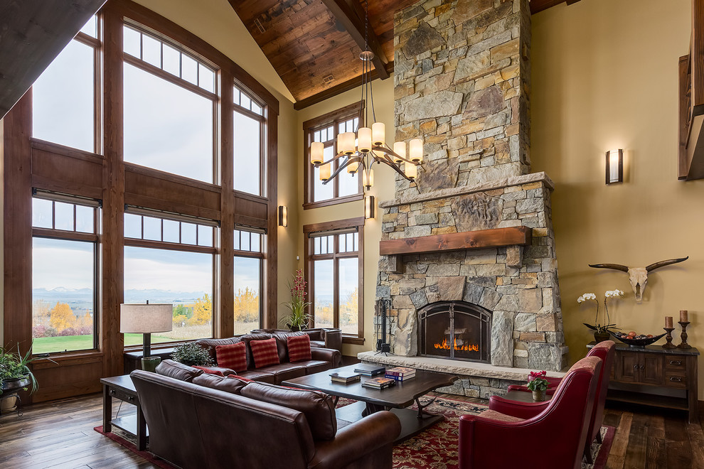 Photo of a large country open concept living room in Calgary with yellow walls, medium hardwood floors, a standard fireplace, a stone fireplace surround, no tv and brown floor.