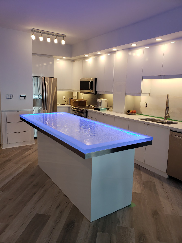 Medium sized modern kitchen/diner in Toronto with an integrated sink, glass-front cabinets, white cabinets, wood worktops, stainless steel appliances, laminate floors, an island, beige floors and white worktops.