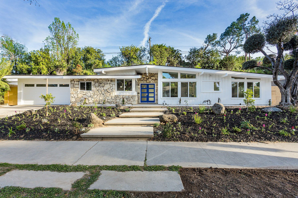 Midcentury one-storey white house exterior in Los Angeles with mixed siding and a gable roof.