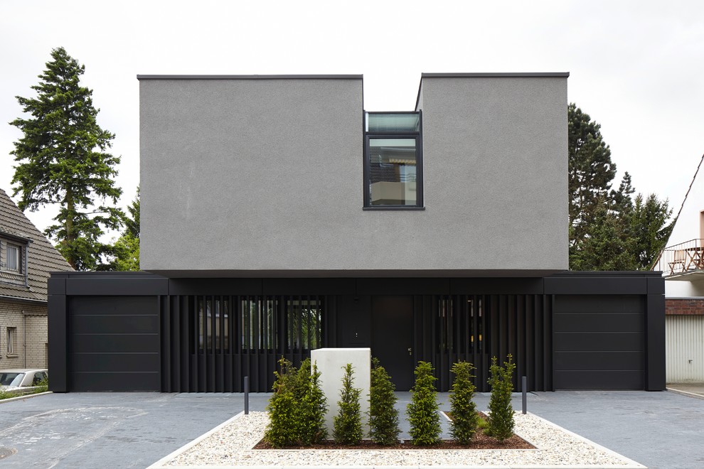 Mid-sized contemporary two-storey grey exterior in Dusseldorf with a flat roof and mixed siding.