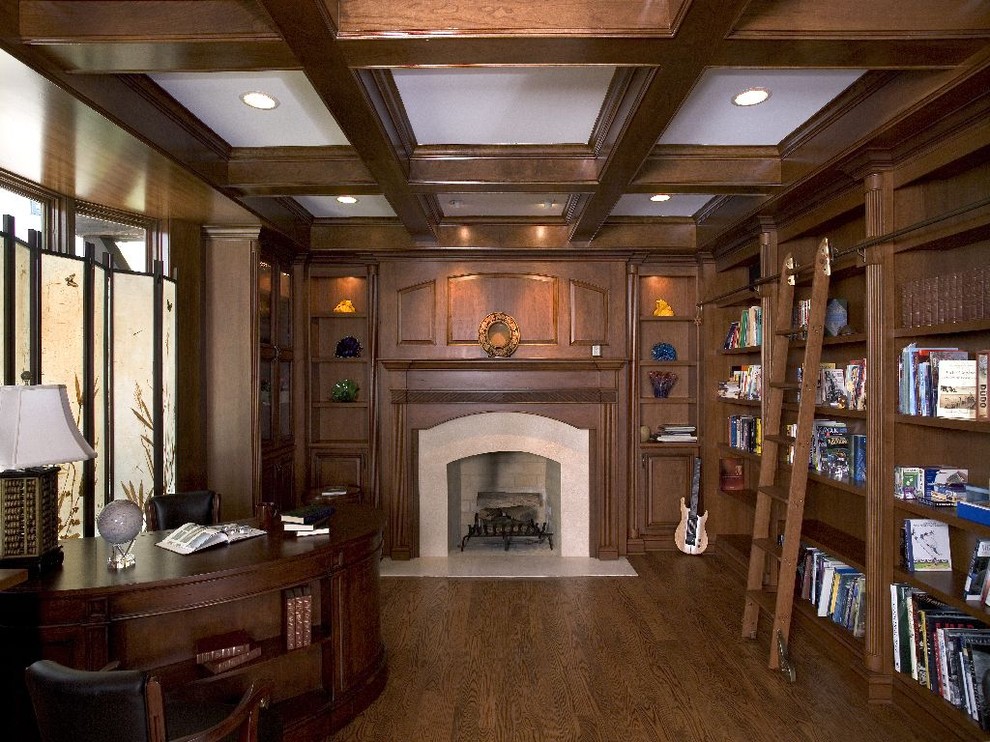 Photo of an expansive traditional home office in Chicago with medium hardwood floors, a standard fireplace, a stone fireplace surround and a freestanding desk.