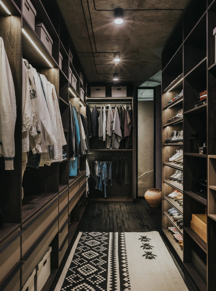 This is an example of a medium sized world-inspired walk-in wardrobe for men in Los Angeles with open cabinets and dark wood cabinets.