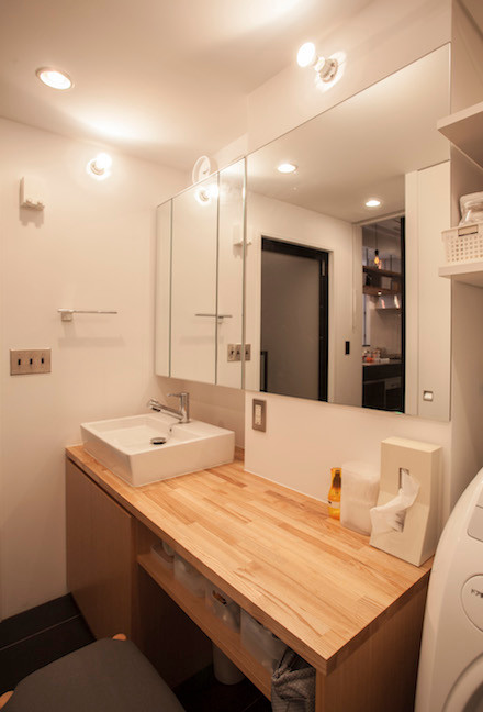 This is an example of a mid-sized modern powder room in Tokyo with flat-panel cabinets, light wood cabinets, white walls, slate floors, a vessel sink and wood benchtops.
