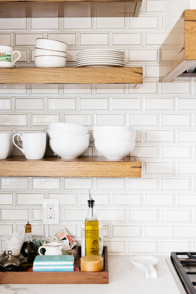 Mid-sized transitional u-shaped medium tone wood floor and brown floor eat-in kitchen photo in Los Angeles with a farmhouse sink, recessed-panel cabinets, white cabinets, quartzite countertops, white backsplash, subway tile backsplash, stainless steel appliances, an island and white countertops