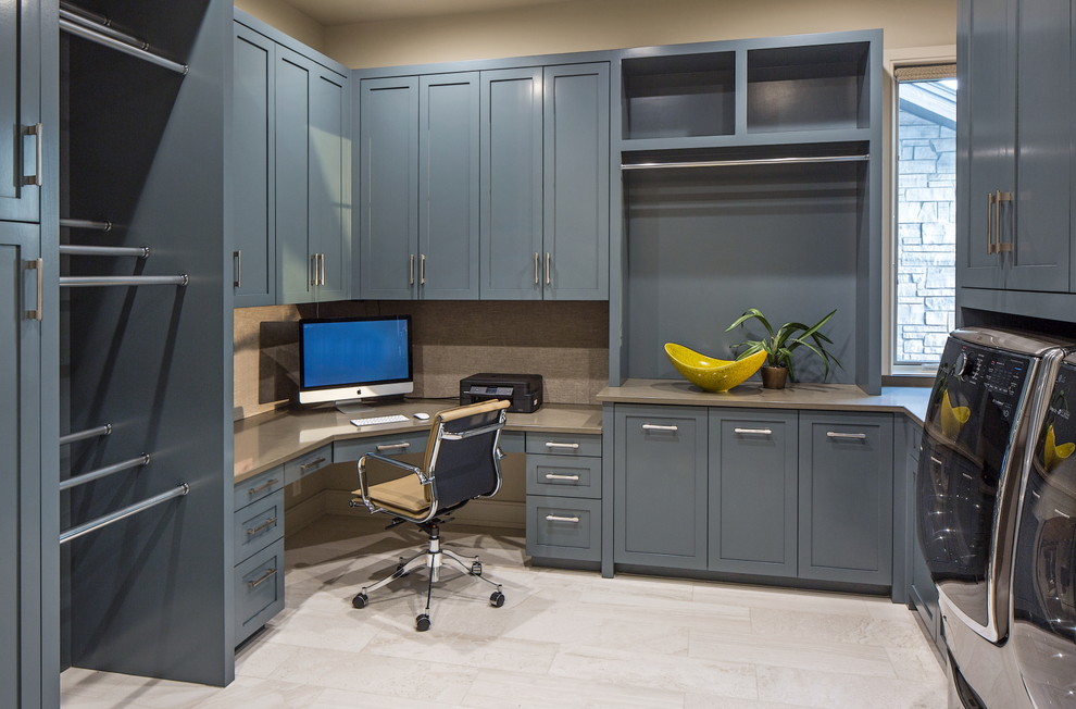 Photo of a large arts and crafts u-shaped utility room in Omaha with shaker cabinets, blue cabinets, quartzite benchtops, beige walls, ceramic floors and a side-by-side washer and dryer.