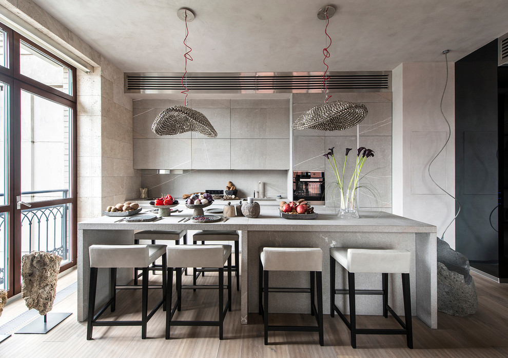 Inspiration for a contemporary galley open plan kitchen in Moscow with flat-panel cabinets, grey cabinets, grey splashback, stone slab splashback, with island, beige floor, an integrated sink, granite benchtops, stainless steel appliances and light hardwood floors.