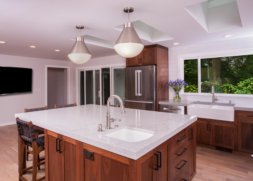 Eat-in kitchen - large transitional u-shaped light wood floor and brown floor eat-in kitchen idea in Seattle with a farmhouse sink, dark wood cabinets, white backsplash, subway tile backsplash, stainless steel appliances, an island and white countertops
