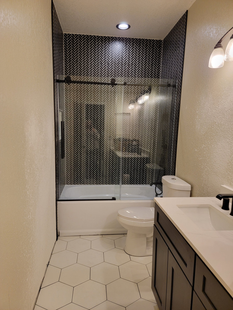 На фото: большая главная ванная комната в стиле модернизм с фасадами в стиле шейкер, темными деревянными фасадами, ванной в нише, душем над ванной, унитазом-моноблоком, черной плиткой, удлиненной плиткой, бежевыми стенами, полом из керамической плитки, врезной раковиной, белым полом, душем с раздвижными дверями, бежевой столешницей, тумбой под одну раковину и встроенной тумбой