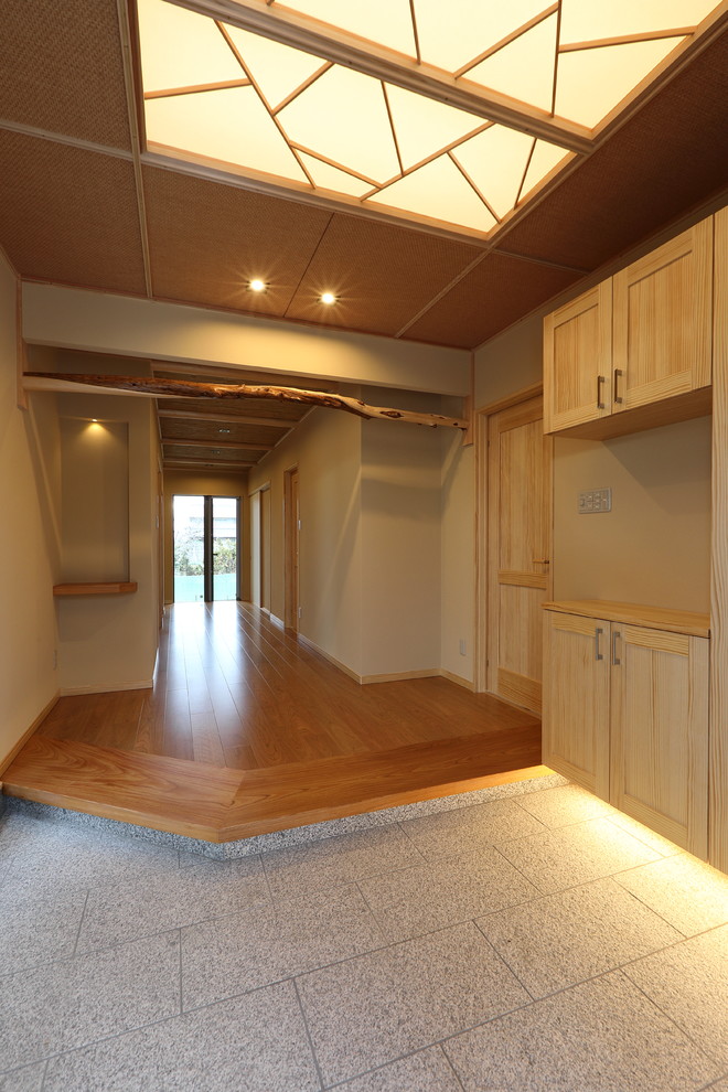 This is an example of a large entry hall in Other with beige walls, granite floors, a sliding front door, a medium wood front door and white floor.