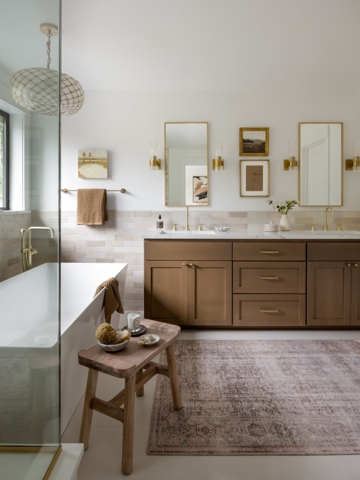 Inspiration for a large transitional master beige tile and ceramic tile porcelain tile, beige floor and double-sink freestanding bathtub remodel in Seattle with shaker cabinets, brown cabinets, a one-piece toilet, white walls, an undermount sink, quartz countertops, a hinged shower door, white countertops and a built-in vanity