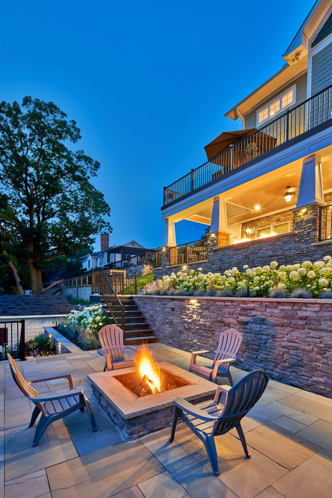 Inspiration for a large arts and crafts backyard patio in Detroit with a fire feature, concrete pavers and an awning.