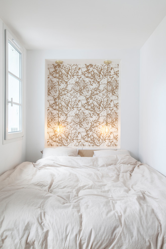 Kleines Nordisches Hauptschlafzimmer ohne Kamin mit weißer Wandfarbe, braunem Holzboden, braunem Boden und Tapetenwänden in Paris