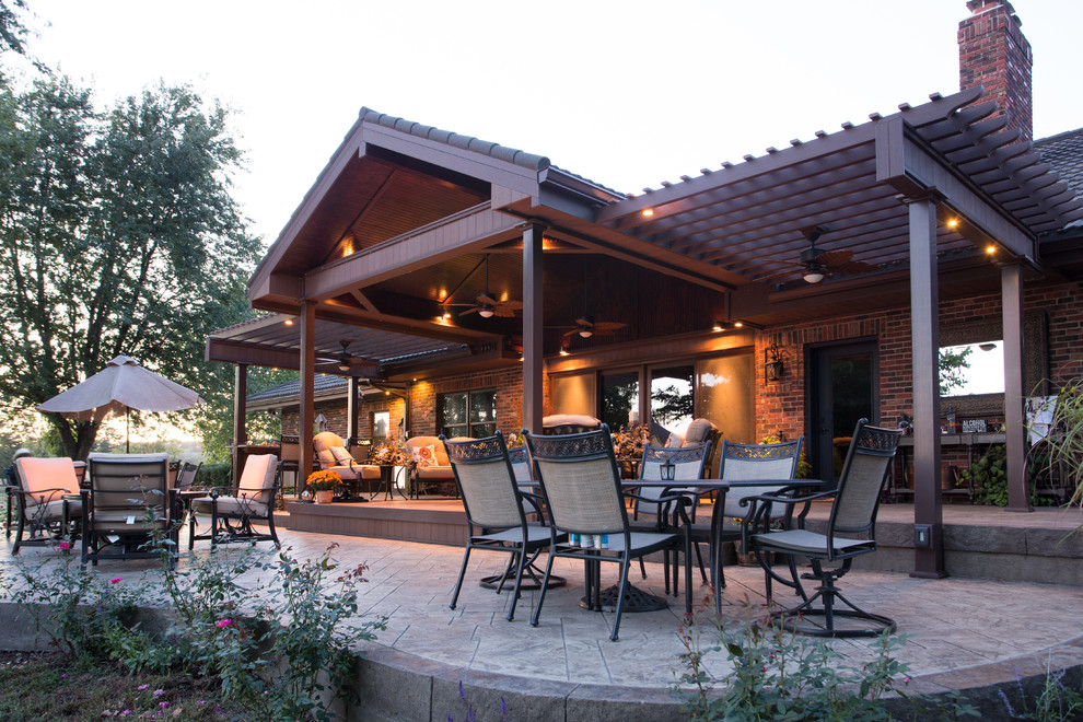 Photo of a large traditional backyard patio in Kansas City with an outdoor kitchen, stamped concrete and a pergola.