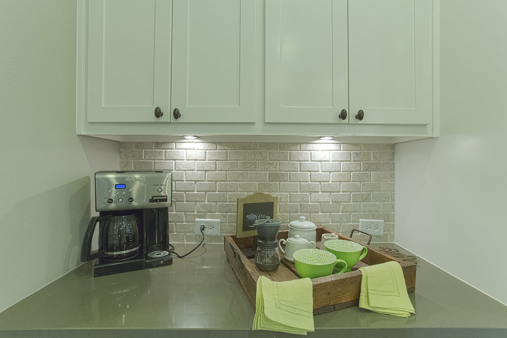 Example of a mid-sized transitional l-shaped dark wood floor and brown floor kitchen pantry design in Dallas with a farmhouse sink, white cabinets, granite countertops, gray backsplash, subway tile backsplash, stainless steel appliances, an island and recessed-panel cabinets