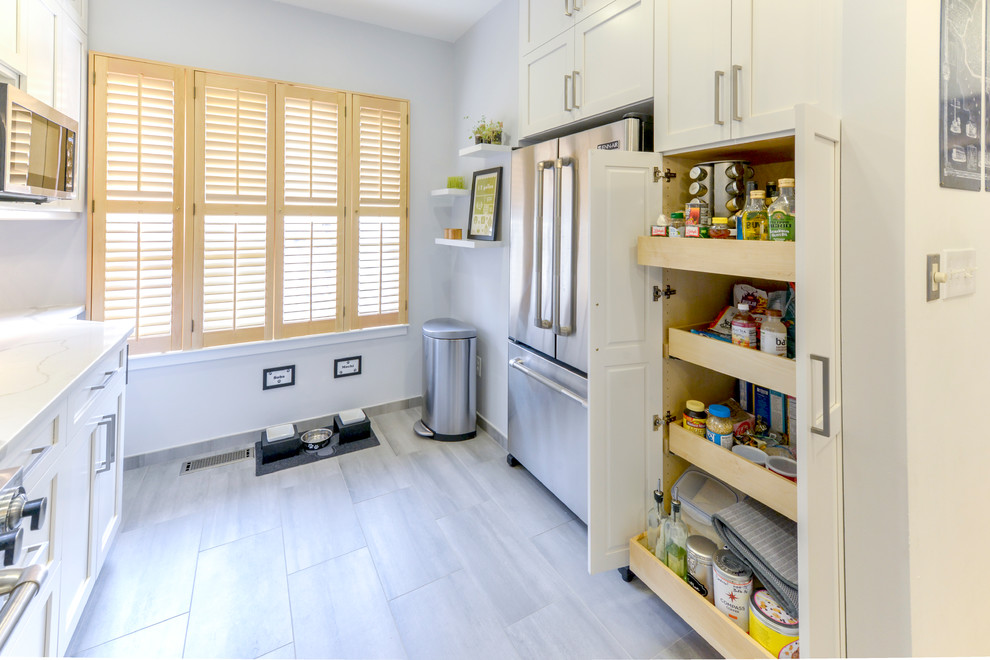 This is an example of a mid-sized contemporary l-shaped kitchen pantry in DC Metro with a farmhouse sink, recessed-panel cabinets, white cabinets, quartz benchtops, blue splashback, subway tile splashback, stainless steel appliances and porcelain floors.