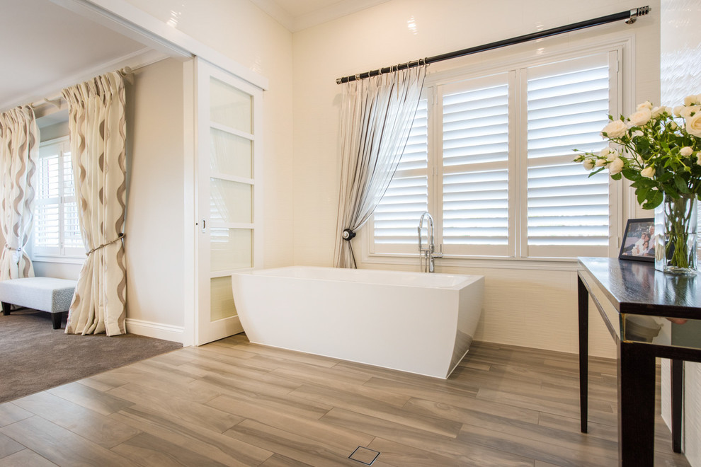 Inspiration for a large contemporary master bathroom in Other with a freestanding tub and light hardwood floors.