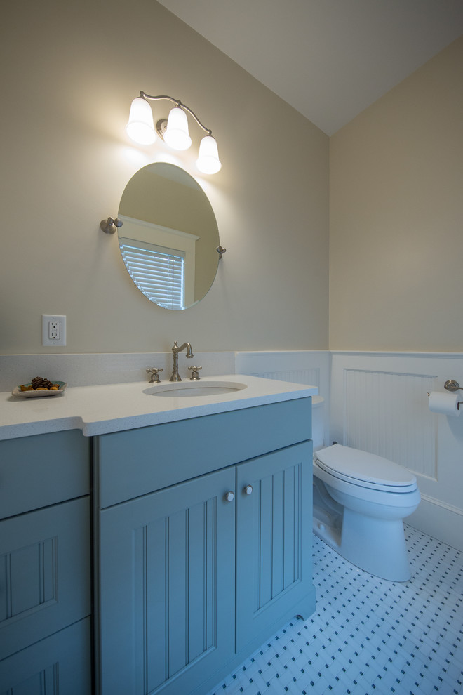 Photo of a small beach style powder room in Boston with turquoise cabinets, a two-piece toilet, beige walls, porcelain floors, an undermount sink, engineered quartz benchtops, white floor and white benchtops.