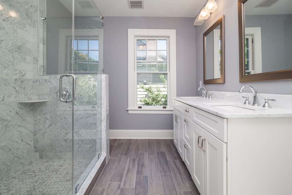 This is an example of a mid-sized traditional 3/4 bathroom in New York with shaker cabinets, white cabinets, an alcove shower, gray tile, marble, grey walls, porcelain floors, an undermount sink, marble benchtops, brown floor and a hinged shower door.