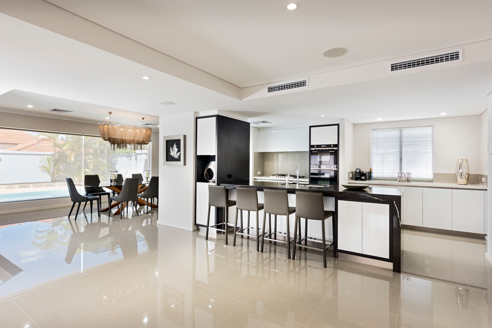Inspiration for a large contemporary galley open plan kitchen in Perth with a double-bowl sink, recessed-panel cabinets, white cabinets, quartz benchtops, white splashback, glass sheet splashback, stainless steel appliances, porcelain floors and multiple islands.