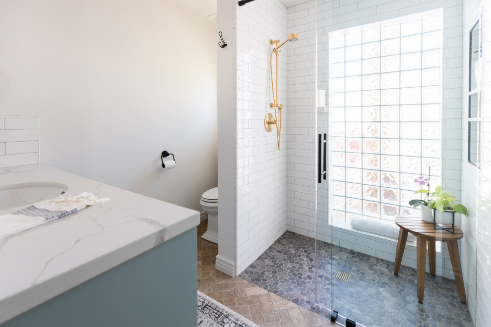 Inspiration for a mid-sized country 3/4 bathroom in Phoenix with shaker cabinets, turquoise cabinets, white tile, subway tile, pebble tile floors, an undermount sink, engineered quartz benchtops, grey floor, a sliding shower screen, white benchtops, a niche, a single vanity and a built-in vanity.