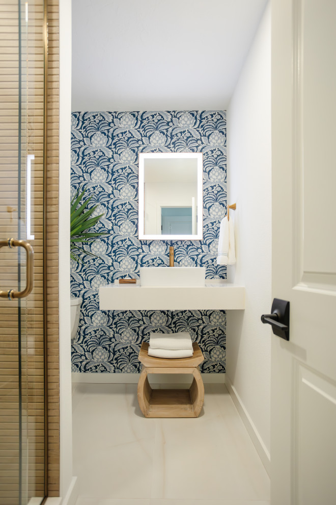 This is an example of a medium sized nautical cloakroom in Tampa with white cabinets, brown tiles, ceramic tiles, blue walls, porcelain flooring, a vessel sink, engineered stone worktops, beige floors, white worktops, a floating vanity unit and wallpapered walls.