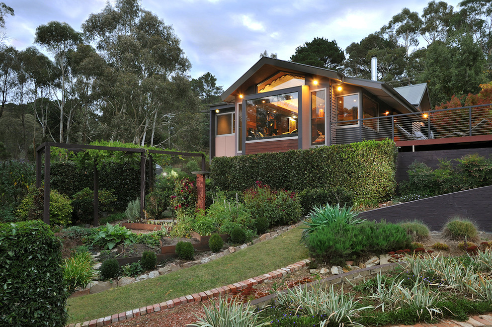 This is an example of an eclectic sloped full sun garden for fall in Melbourne with a retaining wall and gravel.