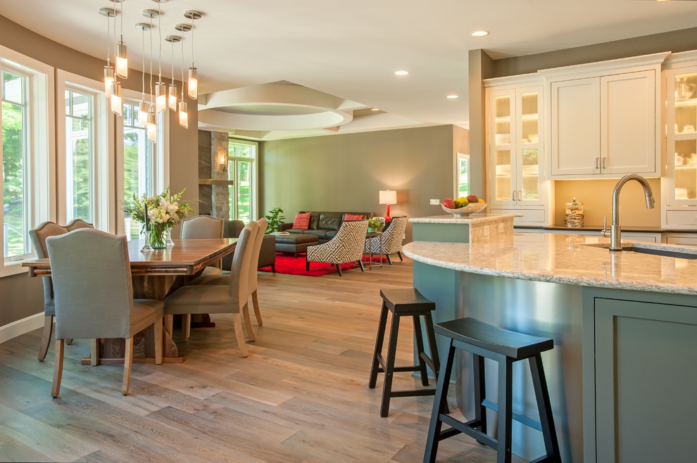 Example of a mid-sized transitional u-shaped medium tone wood floor open concept kitchen design with an undermount sink, shaker cabinets, white cabinets, granite countertops, beige backsplash, stainless steel appliances and an island