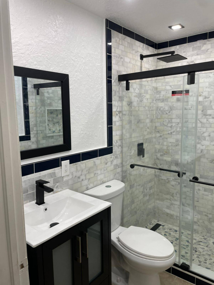 This is an example of a small beach style bathroom in Miami with shaker cabinets, black cabinets, an alcove shower, a two-piece toilet, white tile, marble, white walls, marble floors, an integrated sink, engineered quartz benchtops, beige floor, a sliding shower screen, white benchtops, a niche, a single vanity and a freestanding vanity.