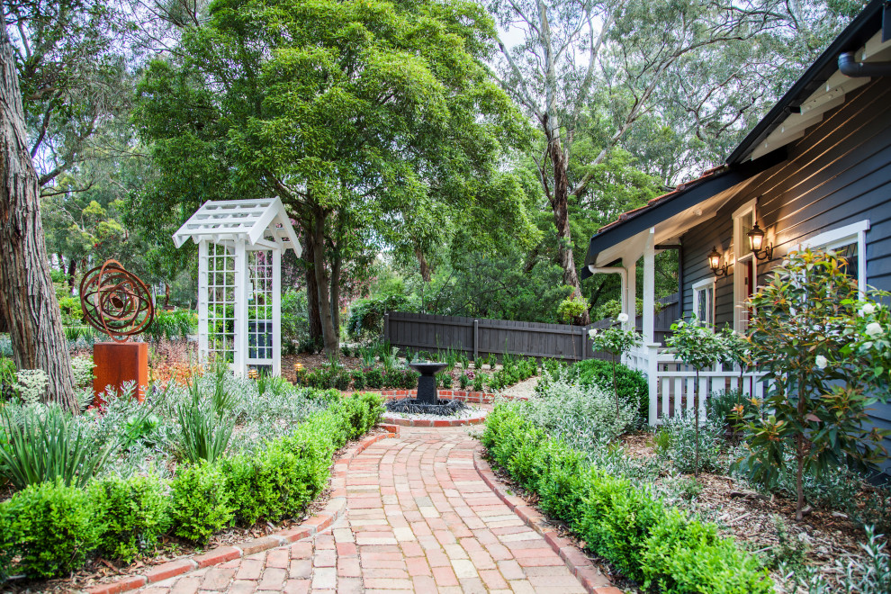 Inspiration for a large traditional front yard full sun garden for spring with brick pavers.