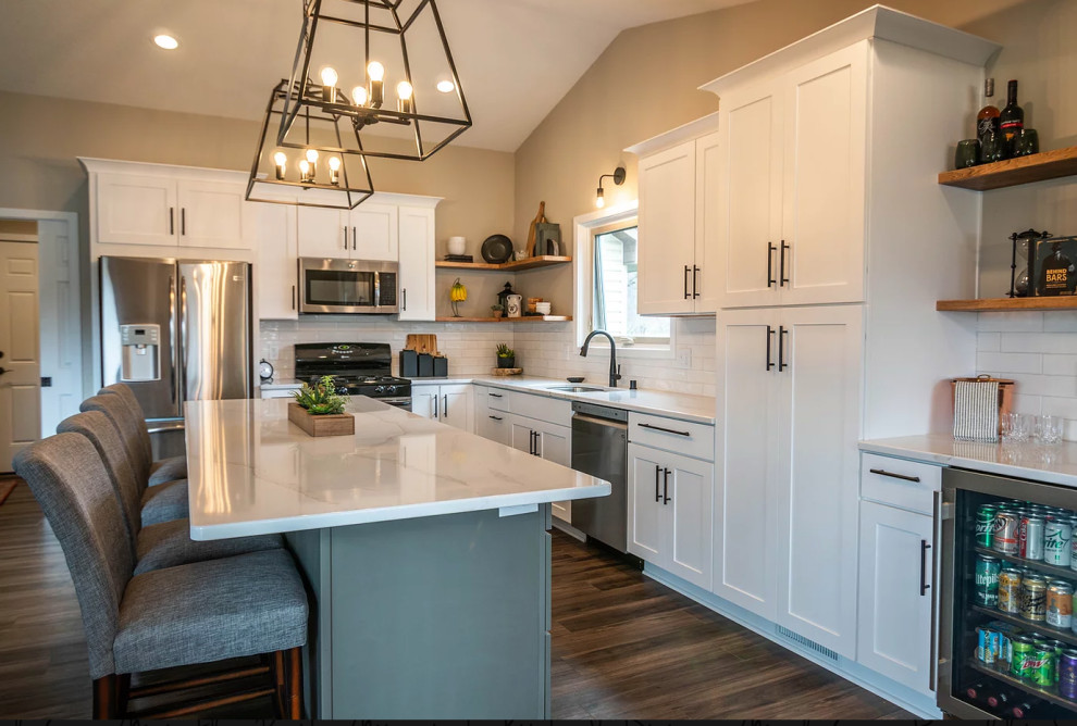 This is an example of a large transitional l-shaped eat-in kitchen in Minneapolis with an undermount sink, shaker cabinets, white cabinets, quartz benchtops, white splashback, ceramic splashback, stainless steel appliances, vinyl floors, with island, brown floor and white benchtop.