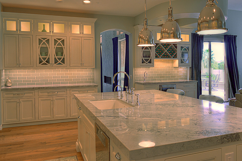 Example of a large transitional l-shaped medium tone wood floor kitchen design in Phoenix with an undermount sink, recessed-panel cabinets, white cabinets, gray backsplash, subway tile backsplash, stainless steel appliances and an island