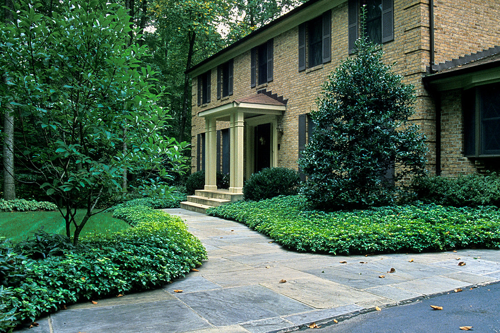 Inspiration for a mid-sized traditional front yard partial sun formal garden in DC Metro with natural stone pavers.
