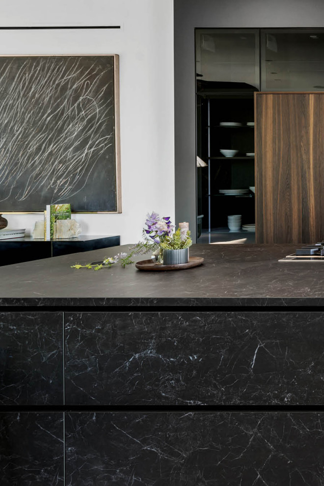 Esempio di una cucina minimalista di medie dimensioni con lavello da incasso, ante lisce, ante nere, top in superficie solida, paraspruzzi nero, paraspruzzi con piastrelle in ceramica, pavimento in laminato, pavimento beige e top nero