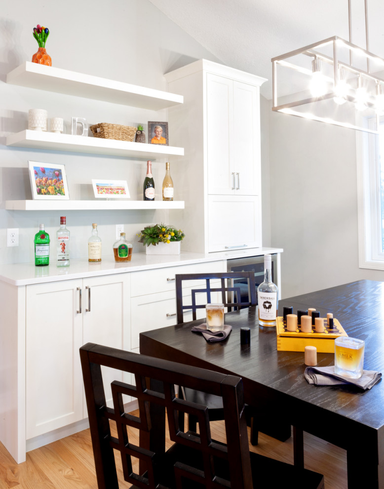 Inspiration for a small transitional single-wall home bar in Minneapolis with recessed-panel cabinets, white cabinets, quartz benchtops, light hardwood floors and white benchtop.