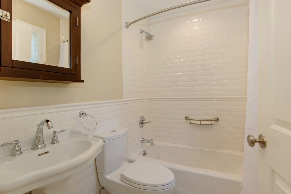 This is an example of a mid-sized transitional kids bathroom in New York with an alcove tub, a shower/bathtub combo, a two-piece toilet, white tile, subway tile, beige walls and a pedestal sink.