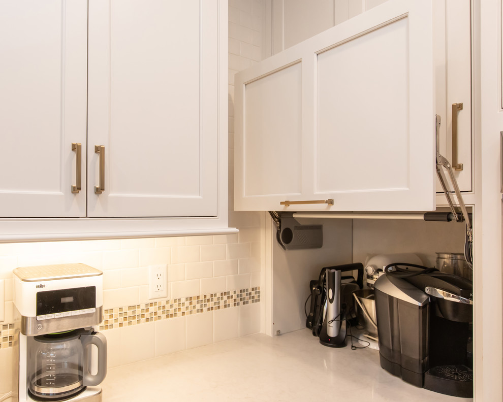 Inspiration for a mid-sized l-shaped laundry room in Boston with an undermount sink, beaded inset cabinets, light wood cabinets, quartz benchtops, white splashback, cement tile splashback, dark hardwood floors, brown floor and white benchtop.