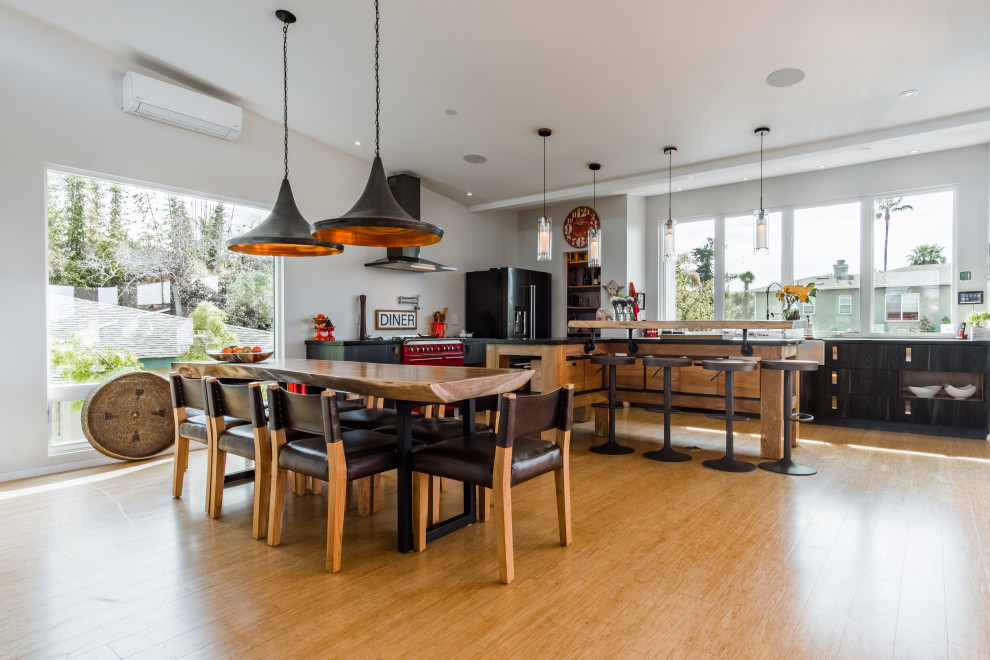 Design ideas for a mid-sized modern l-shaped open plan kitchen in San Diego with flat-panel cabinets, black cabinets, black appliances, bamboo floors, with island, black benchtop and vaulted.
