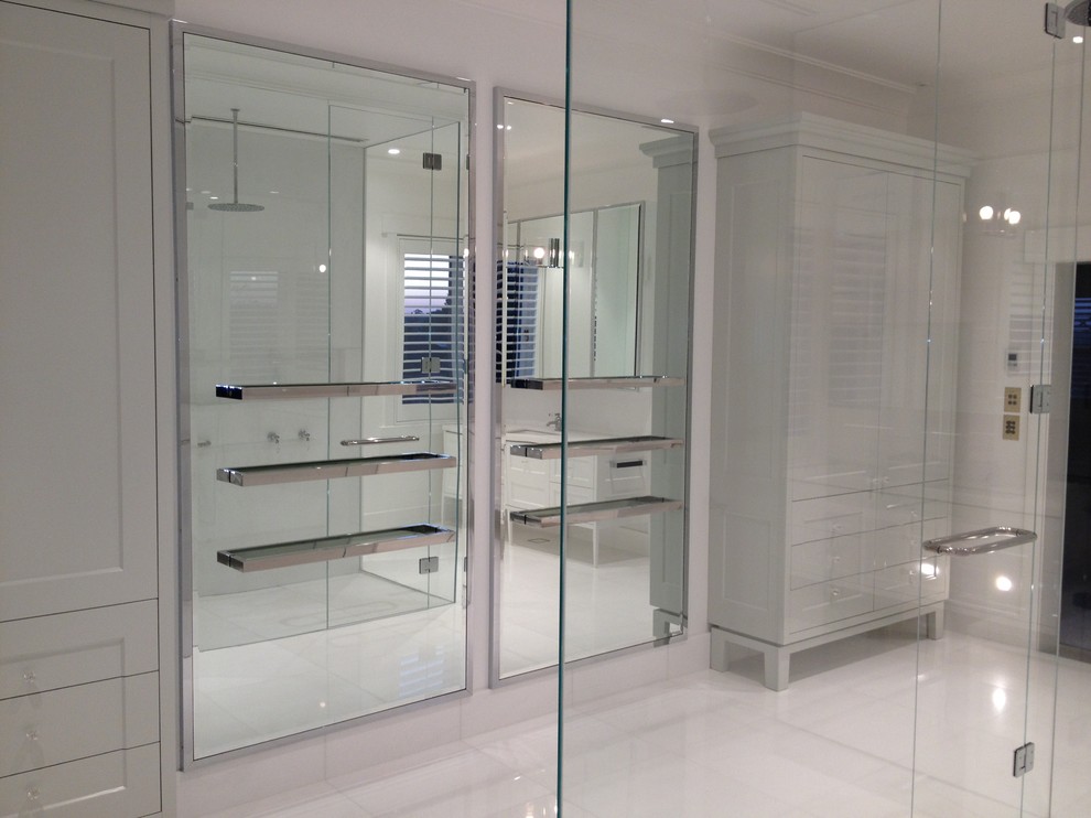 Expansive modern master bathroom in Melbourne with recessed-panel cabinets, an undermount sink, grey cabinets, marble benchtops, a double shower, a wall-mount toilet, white tile, stone tile, white walls and marble floors.
