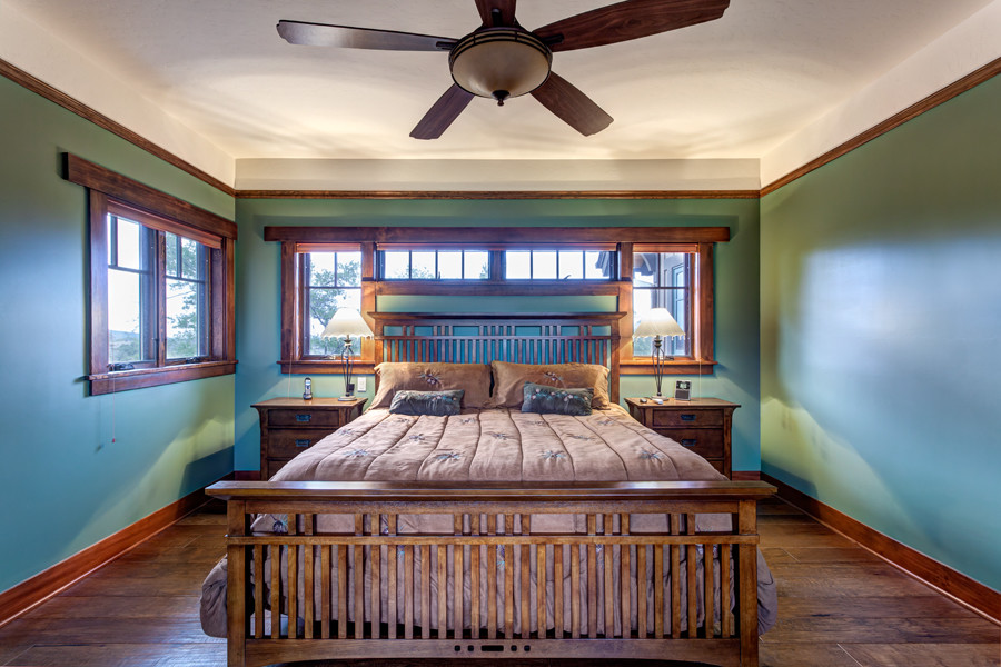 This is an example of a large arts and crafts master bedroom in Phoenix with green walls, medium hardwood floors, no fireplace and brown floor.