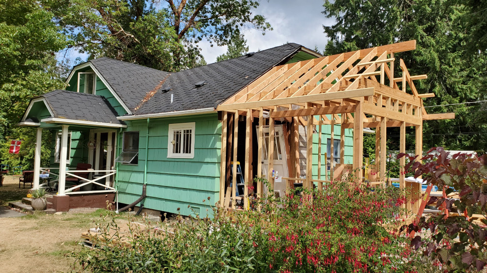 Réalisation d'une petite façade de maison verte craftsman en bois et bardeaux à un étage avec un toit à croupette, un toit en shingle et un toit noir.