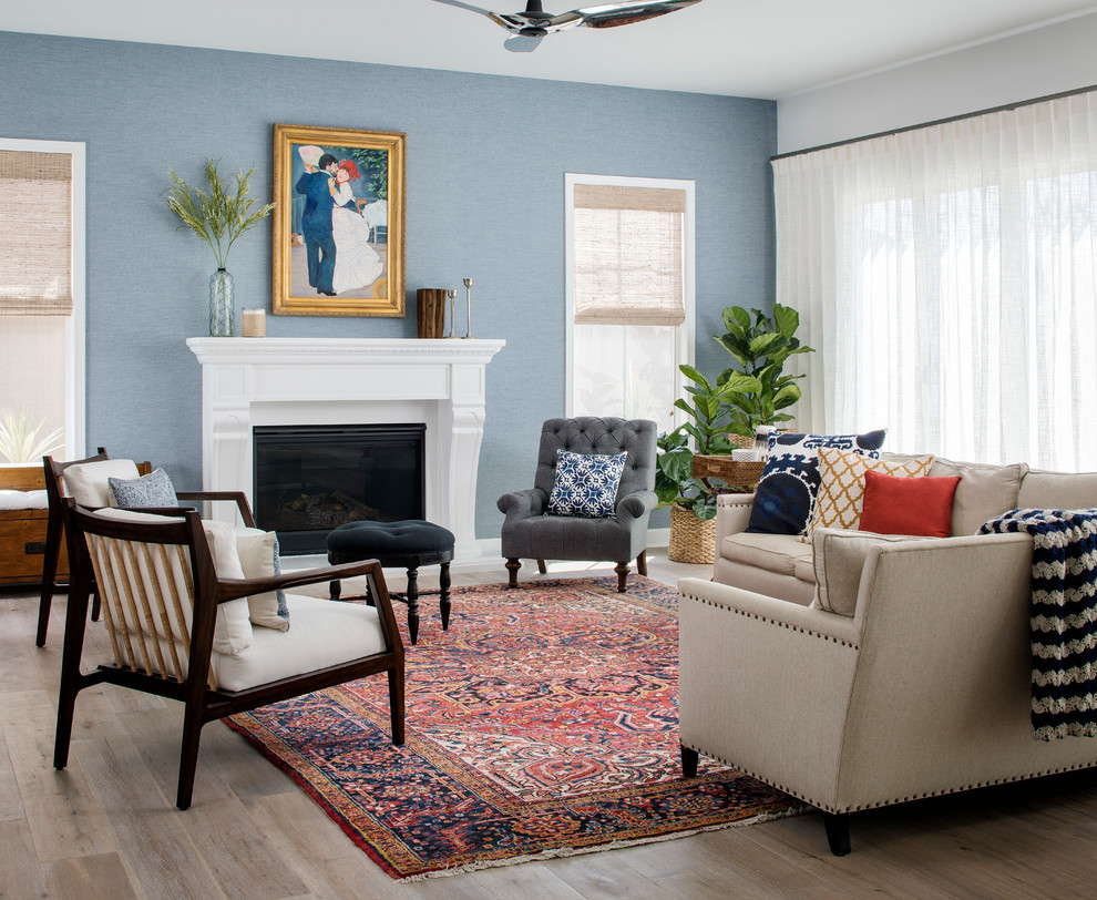 Photo of a mid-sized beach style open concept living room in San Francisco with blue walls, light hardwood floors, a standard fireplace, no tv and a plaster fireplace surround.