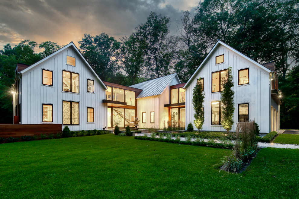 Cette photo montre une façade de maison blanche nature en bois et bardage à clin à un étage avec un toit à deux pans, un toit en métal et un toit gris.