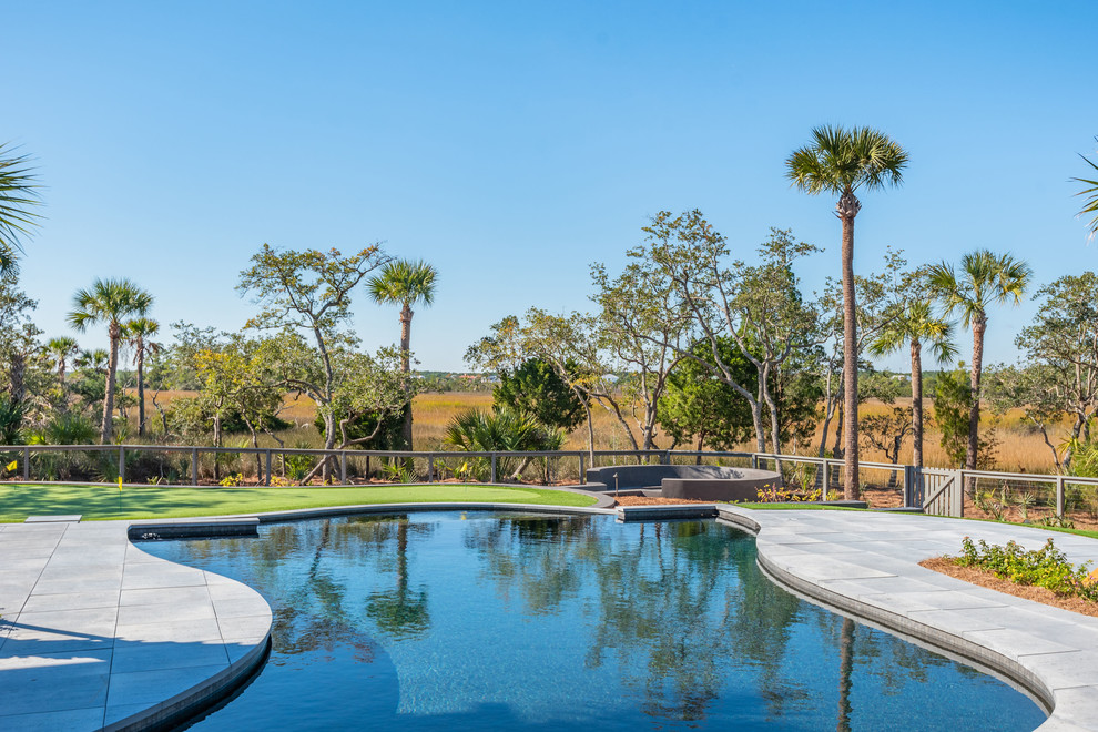 Photo of a large modern backyard kidney-shaped infinity pool in Charleston with concrete pavers.
