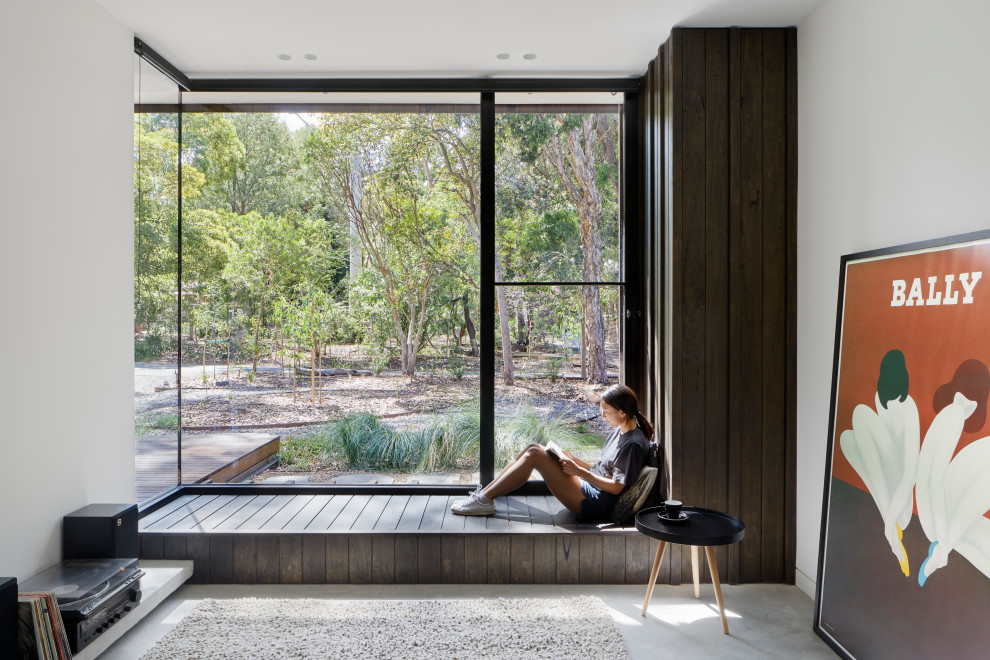 Inspiration for a mid-sized contemporary enclosed living room in Melbourne with a library, white walls, concrete floors, a wall-mounted tv and grey floor.