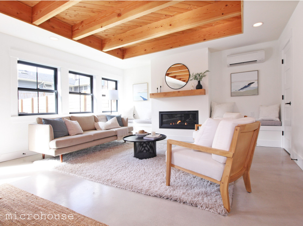 シアトルにある高級な小さなトラディショナルスタイルのおしゃれなリビング (コンクリートの床、標準型暖炉、漆喰の暖炉まわり、グレーの床、表し梁) の写真