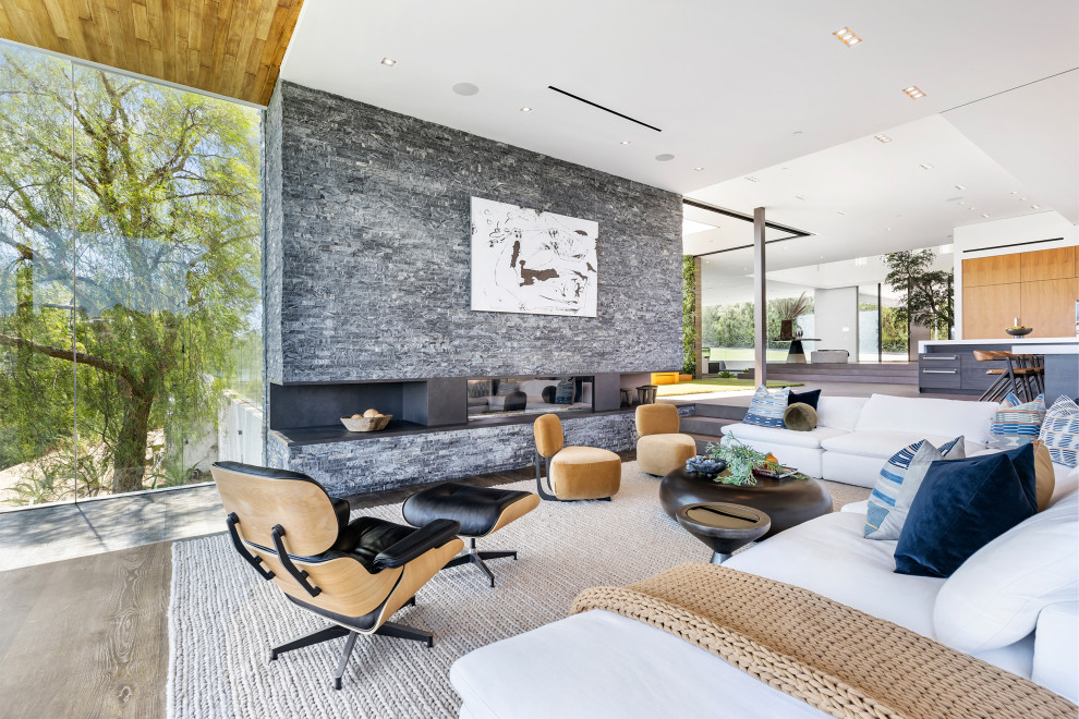 Идея дизайна: огромная открытая гостиная комната в стиле модернизм с стандартным камином и фасадом камина из каменной кладки без телевизора