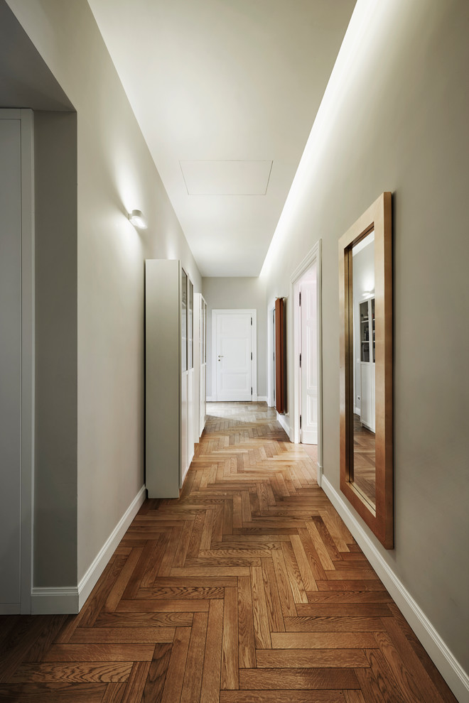Photo of a large transitional hallway in Rome with green walls, medium hardwood floors and brown floor.