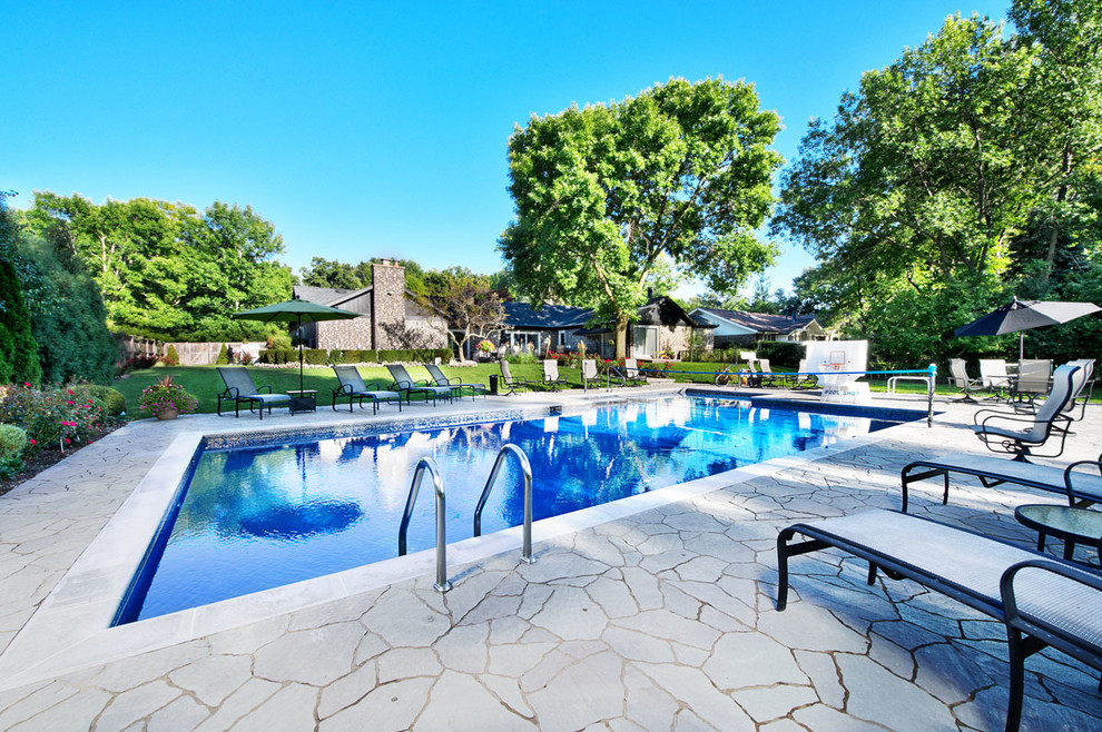 Design ideas for a mid-sized traditional backyard rectangular lap pool in Chicago with concrete pavers and a hot tub.