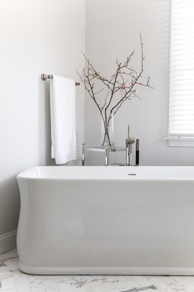 Inspiration for a transitional master beige tile and mosaic tile marble floor and gray floor freestanding bathtub remodel in Boston with recessed-panel cabinets, white cabinets, a one-piece toilet, white walls, an undermount sink, quartz countertops, a hinged shower door and beige countertops